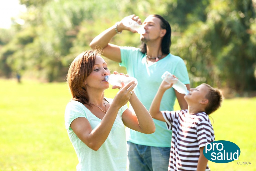 Happy family drinking water from plastic bottles in summer park